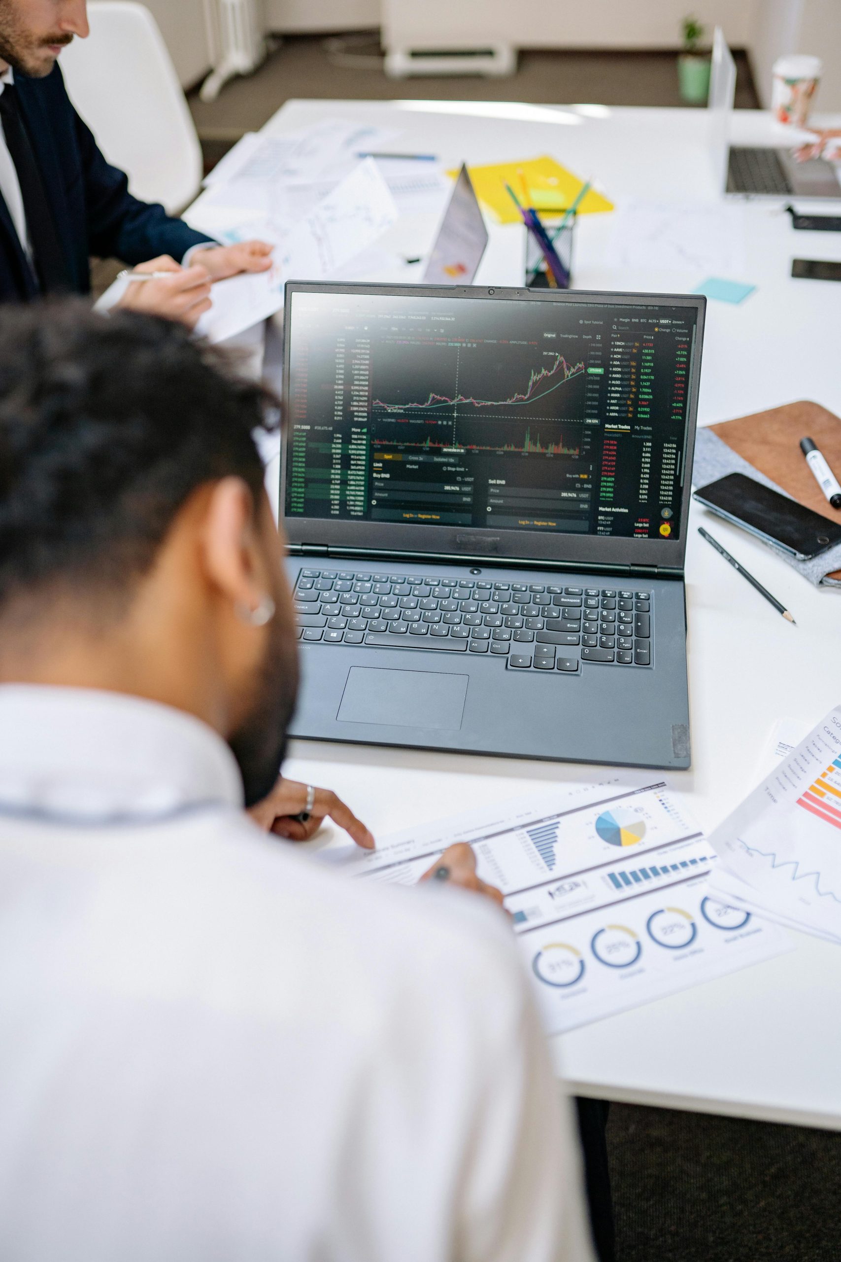Home Business professionals analyzing stock charts and graphs on a laptop in an office setting.